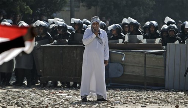 An Egyptian man stands in front of riot police blocking the road during clashes with protestors near the Interior Ministry in Cairo, Egypt, on Saturday.